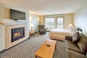 Ein Hotelzimmer mit Kamin, Bett, Sofa, Fernseher und Meerblick.