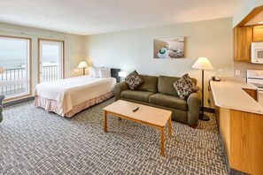 Une chambre d’hôtel comprenant un lit, un canapé, une petite table, un coin cuisine et un balcon avec vue.