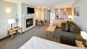 Een hotelkamer met een open haard, een eethoek, een keuken en een zithoek.