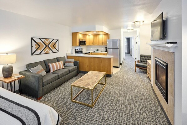 A modern living room with a sofa, coffee table, and a kitchen in the background.