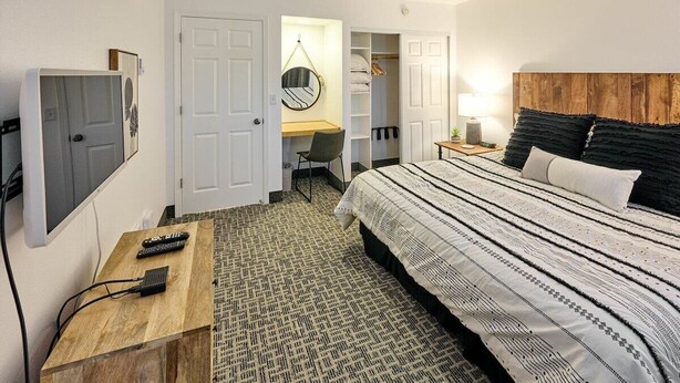 A bedroom with a bed, bedside table, desk, chair, wardrobe, and a mirror. - Oceanfront Suite - King Bed - Heated Indoor Pool & Hot Tub (Lincoln City)