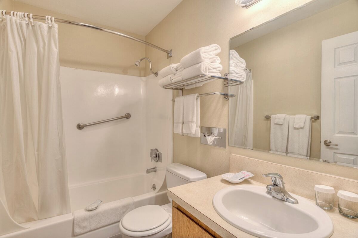 Un bagno con vasca, water, lavabo e un porta asciugamani con asciugamani piegati.