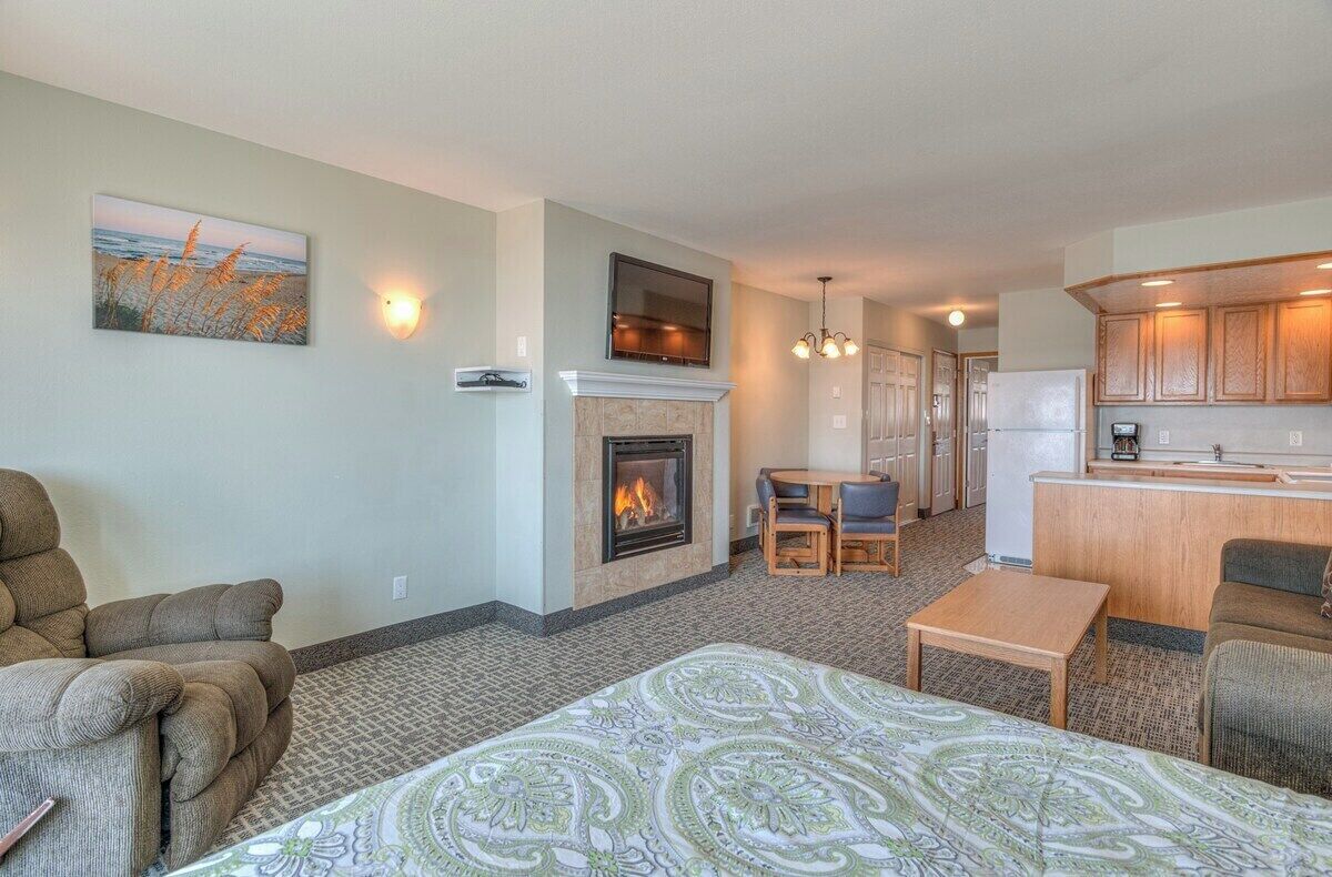 A living room with a fireplace, a dining area, and a kitchen with wooden cabinets.