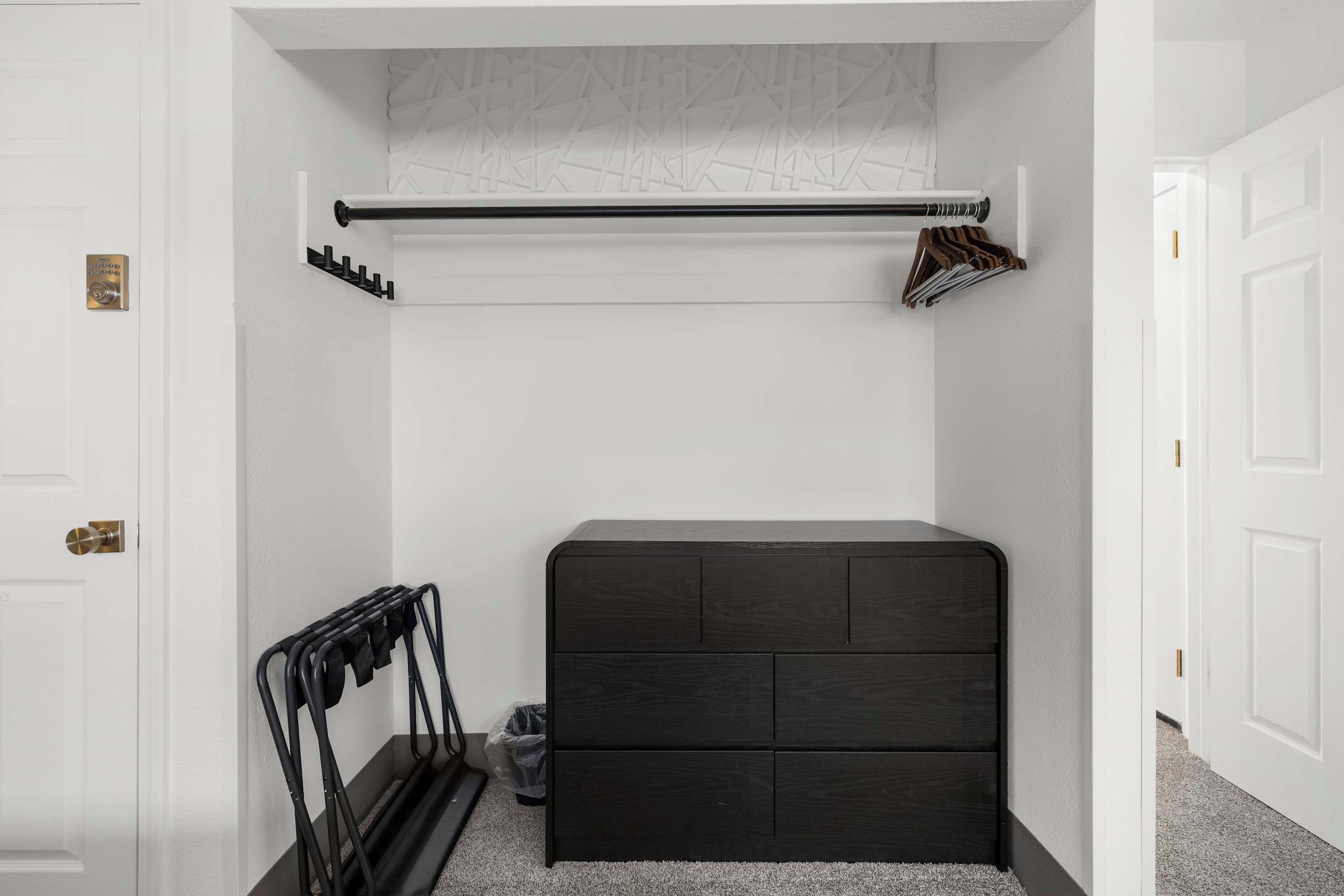 Una habitación con un aparador de madera oscura, un perchero y una puerta blanca.