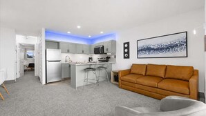 A modern apartment with a kitchen, a living area with a sofa, and a dining area with chairs. - Corner King Suite, Stunning Ocean and River Views! (Lincoln City)