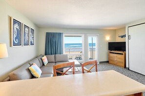Une chambre d’hôtel avec un balcon, un canapé, une table à manger et un téléviseur.