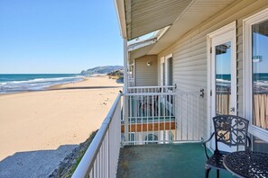 Blick auf den Strand von einer Veranda mit Tisch und Stuhl, mit Blick aufs Meer.