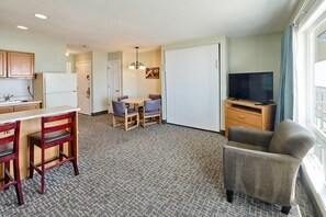 A compact hotel room with a kitchenette, a dining area with a table and chairs, a television, and a large window. - Oceanfront Family Suite - Full Kitchen - Easy Beach Access! (Lincoln City)