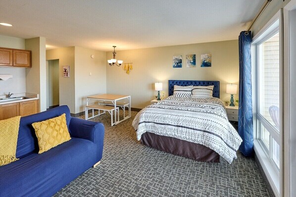 Une chambre d’hôtel avec un lit, un canapé, une petite table et une fenêtre avec des rideaux.