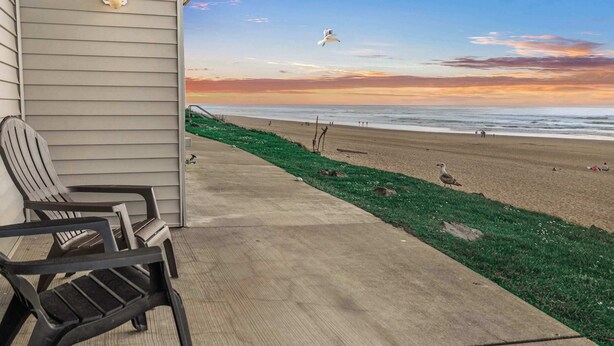 Een uitzicht op het strand met stoelen en een lamp op een veranda.