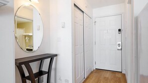A hallway with a mirror, a door, and a wooden floor. - Ground Floor Condo - Ocean View - Pool & Hot Tub! (Lincoln City)