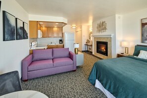 Une chambre d’hôtel avec un canapé, un lit, une cheminée et une kitchenette.