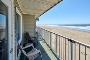 Un balcon avec vue sur la plage, une chaise et une table.