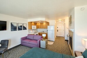 Una habitación de hotel con kitchenette, un sofá, una silla y una cama.