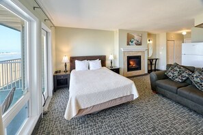 A hotel room with a bed, a sofa, a fireplace, and a view of the ocean. - Fireplace Queen Studio - Ocean View - Pool & Hot Tub! (Lincoln City)