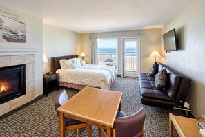 A hotel room with a fireplace, a bed, a sofa, a table, and a TV.