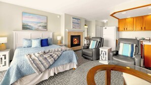A bedroom with a bed, a fireplace, a seating area, and a kitchen. - Ground Floor Studio - Ocean View - Pool & Hot Tub! (Lincoln City)