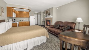 Une chambre d’hôtel comprenant un lit, un canapé en cuir marron, une table à manger, une cheminée et un coin cuisine.