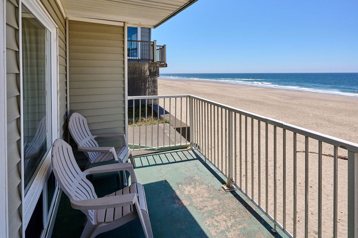 A balcony with two chairs and a view of the beach.