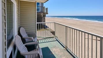 A balcony with two chairs and a view of the beach.