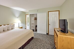 A hotel room with a bed, a television on a wooden dresser, a wardrobe, and a lamp on a nightstand. - Corner Oceanview King Suite, Full Kitchen, Beach Access, Pool & Hot Tub! (Lincoln City)