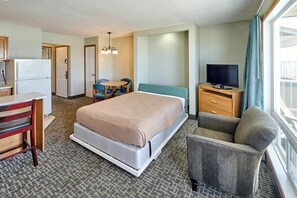 Ein Hotelzimmer mit einem Bett, einem Schreibtisch, einem Stuhl, einem Fernseher und einem Fenster mit Vorhängen.