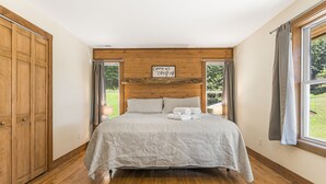 A bedroom with a wooden headboard, a bed with a patterned bedspread, and a sign above the bed.