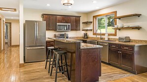 A modern kitchen with stainless steel appliances, wooden cabinets, and a large island with bar stools.
