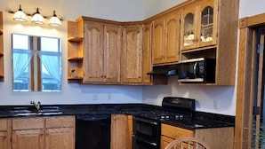 A kitchen with wooden cabinets, a black stove, and a dining table with chairs. - Haven Point is Spacious and Great for Families.  2nd floor apartment. (Strawberry Point)