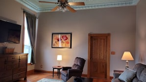 A living room with a ceiling fan, a television, a wooden cabinet, a chair, a sofa, a table, and a door. - Haven Point is Spacious and Great for Families.  2nd floor apartment. (Strawberry Point)