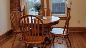 A dining area with a wooden table and chairs, a potted plant, and a view through a window with sheer curtains. - Haven Point is Spacious and Great for Families.  2nd floor apartment. (Strawberry Point)