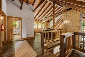 A wooden interior with a stone wall, a wooden staircase, and a view through a window.