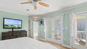 Una camera da letto con un letto, una televisione, una ventola a soffitto e vista sull'esterno tramite una porta scorrevole.