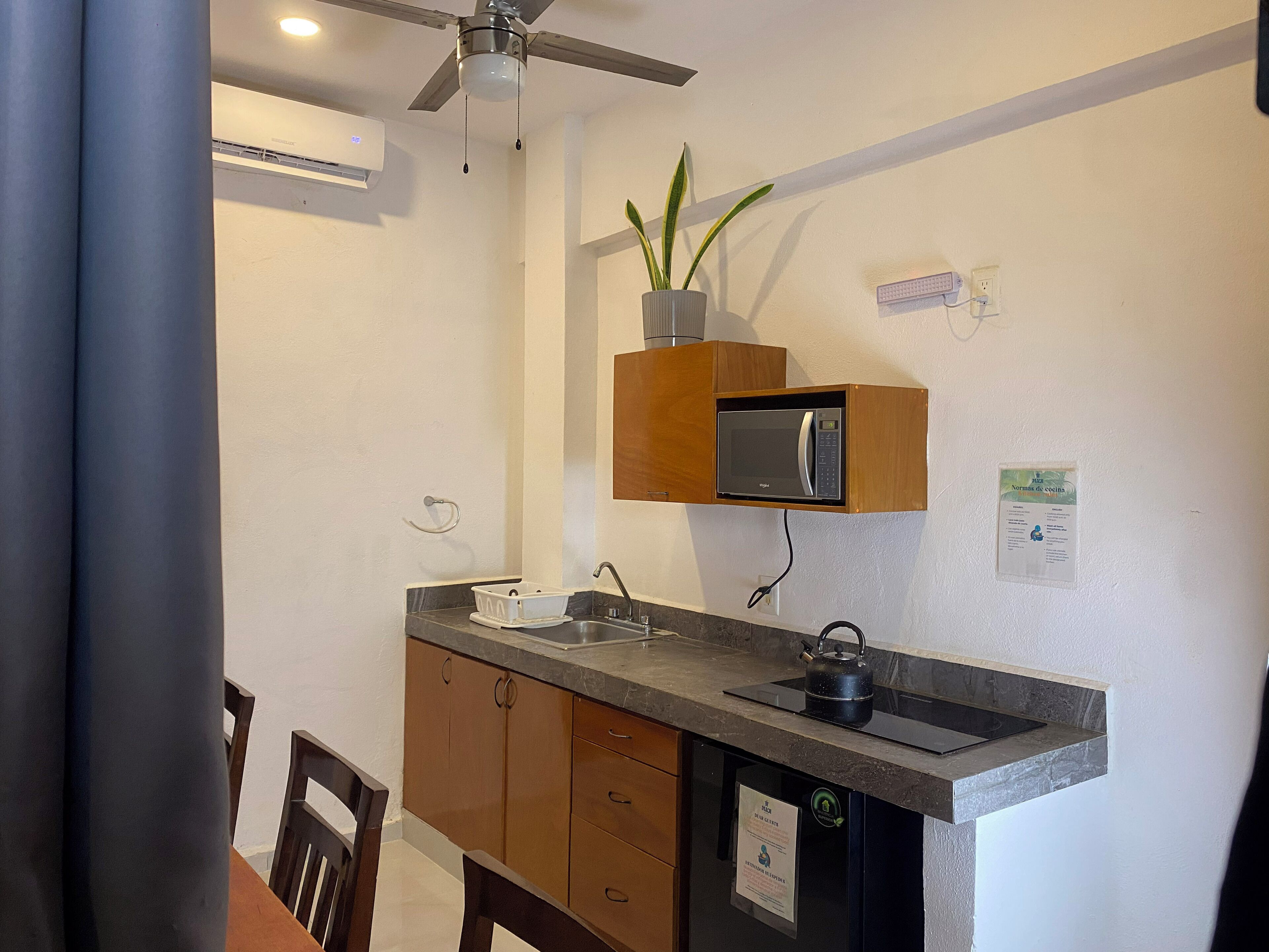 A compact kitchen with a built-in microwave, a sink, and a ceiling fan.