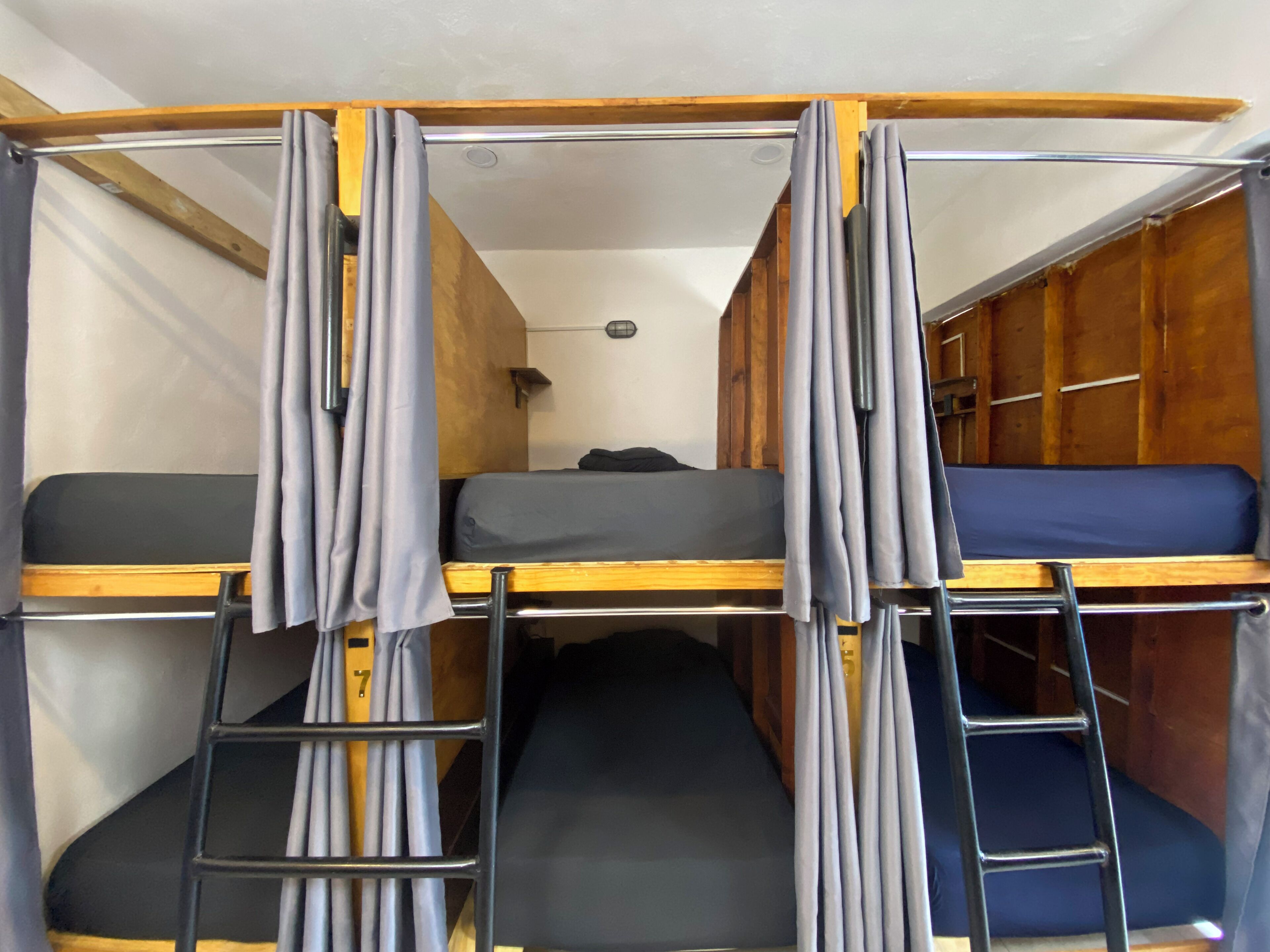 Une chambre avec un lit superposé, une échelle, des murs en bois et un petit bureau avec une lampe.