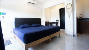 Un dormitorio con una cama de madera, un escritorio, una silla y un atrapasueños en la pared.