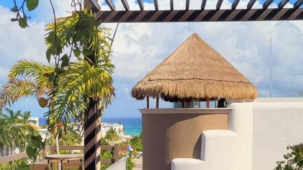 Un área de piscina con sillas de descanso y una estructura con techo de paja.