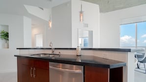 Una cocina moderna con lavavajillas de acero inoxidable, encimera negra y un amplio ventanal que proporciona luz natural.