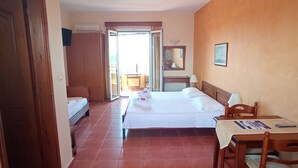 Habitación de hotel con cama, escritorio, silla, armario y baño visible a través de una puerta abierta.