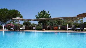 Una piscina azul cristalina con sillas de descanso y sombrillas.