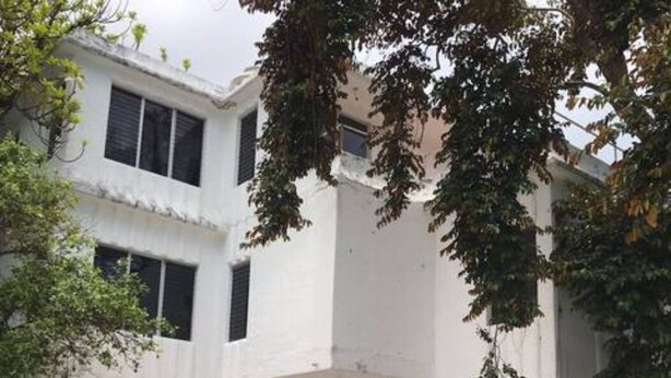 Um edifício de dois andares com fachada simétrica, janelas grandes e entrada central com porta preta.