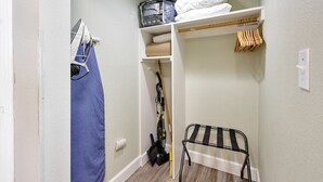 A walk-in closet with shelves, a hanging rack, and a vacuum cleaner.