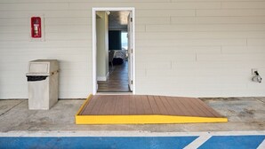 A room with a doorway leading to a hallway, a small trash bin, and a ramp with a yellow edge.