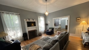 A living room with a fireplace, a sofa, a dining table, and a chandelier.