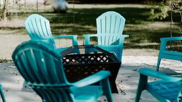 A set of turquoise Adirondack chairs arranged around a black wicker table on a concrete surface.