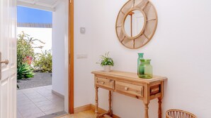 A wooden console table with a mirror, a potted plant, and a green vase against a white wall. - Amazing 3 bedroom Ocean view with pool (Tías)