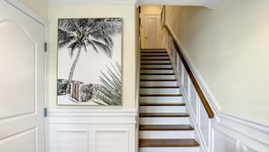 A staircase with white walls and a framed black and white painting of a palm tree. - Stunning Waterfront Penthouse with Rooftop Casita – Steps to Clearwater Beach (Clearwater)