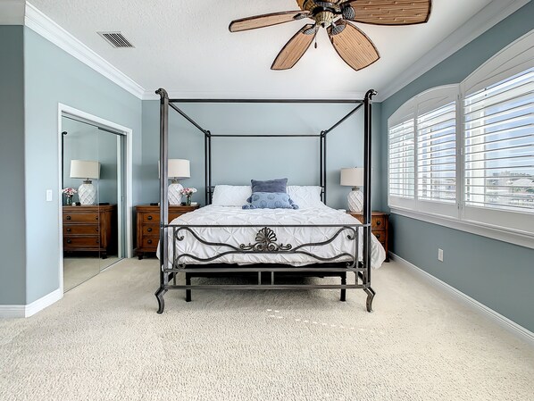 A four-poster bed with a canopy, a ceiling fan, and a large window with blinds. - Stunning Waterfront Penthouse with Rooftop Casita – Steps to Clearwater Beach (Clearwater)