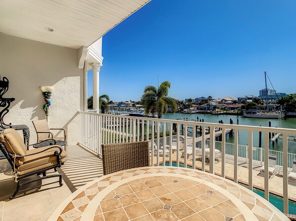 Un balcon avec vue sur une marina, une piscine et une chaise.