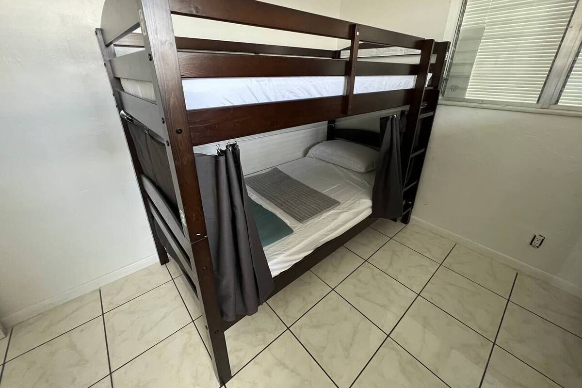 A bunk bed with a wooden frame and white bedding.